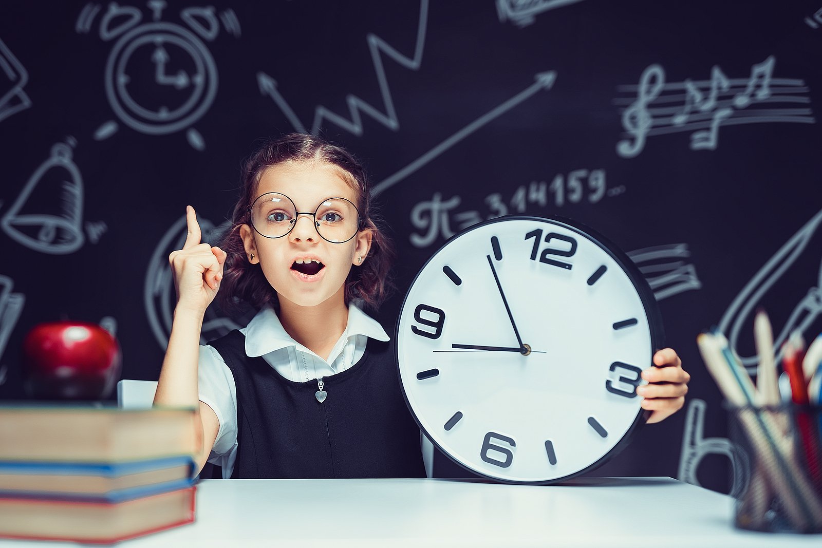 Pupil Girl With Big Clock At The Black Chalkboard In Classroom.