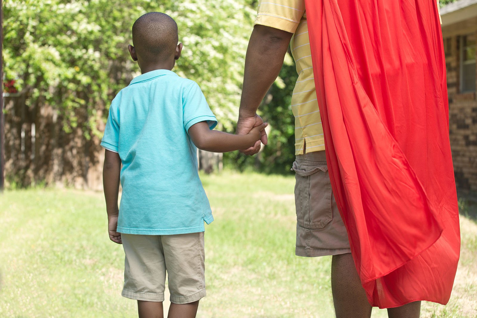 African American little boy super hero playing outside.